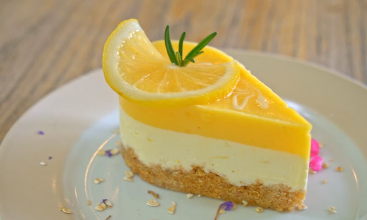 Taça de sobremesa com creme de limão amarelo claro, decorado com raspas de limão e uma rodela fina da fruta.