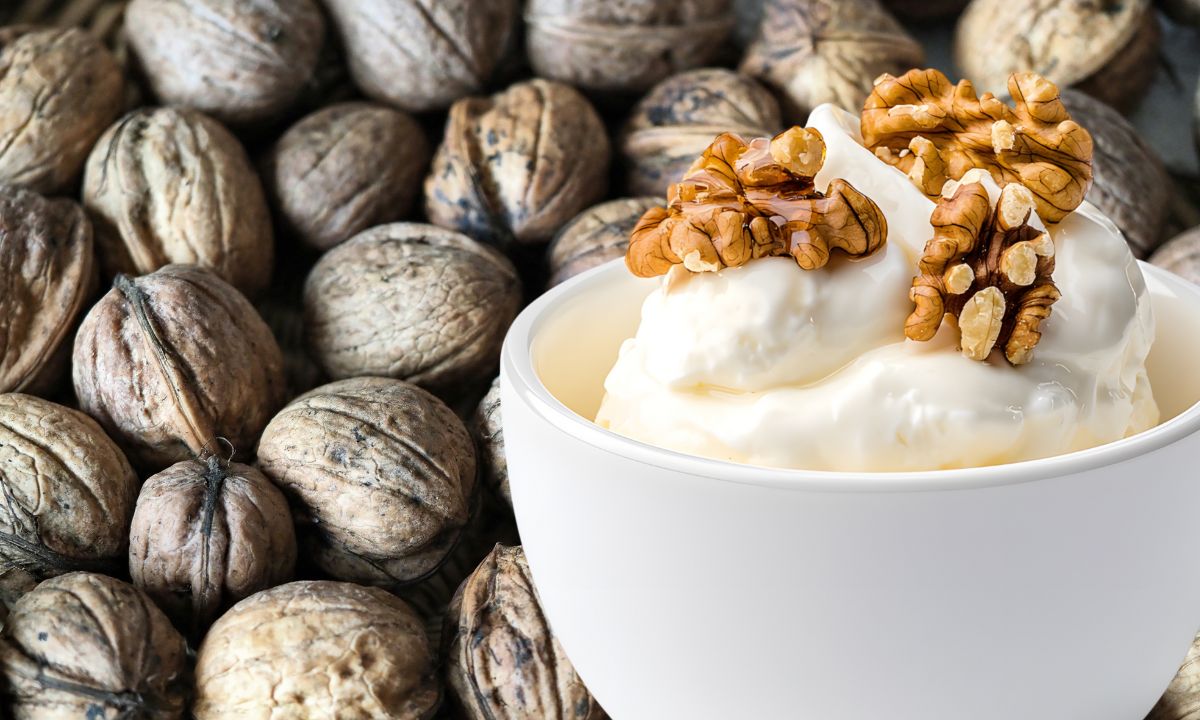 Tigela com creme de nozes espesso e bege-dourado, com pedacinhos visíveis de nozes trituradas.