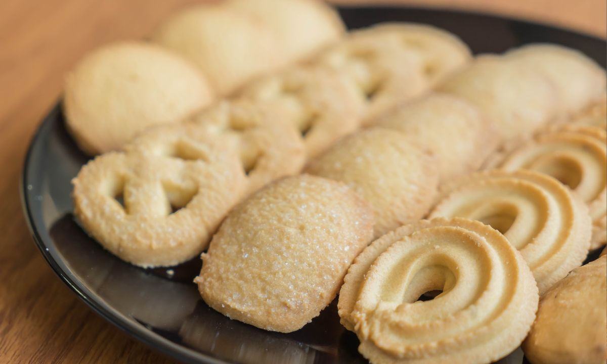 Biscoitos sequilhos redondos e claros, com a marca do garfo em cima, servidos em um prato.